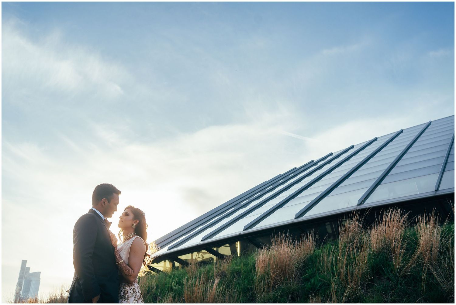 Sunset silhouette against a modern building with solar panels on the rooftop.