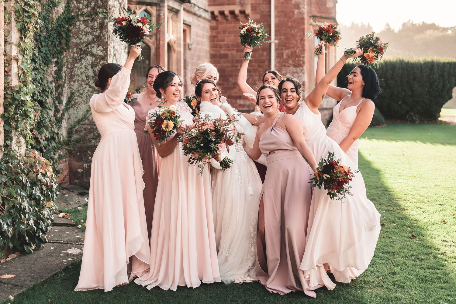 Bride and bridesmaids in pink dresses celebrating outdoors at a country manor, candid wedding group photography Southampton