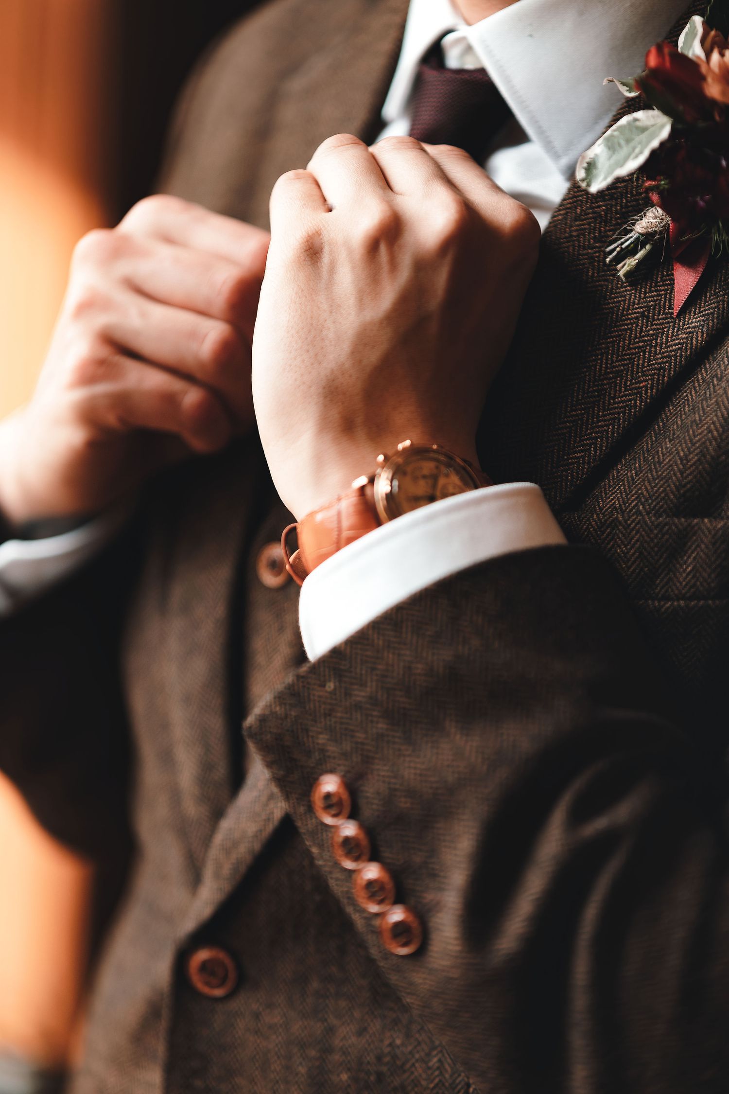 Close-up of groom adjusting cuffs showing tweed suit and boutonniere, wedding detail photography Southampton