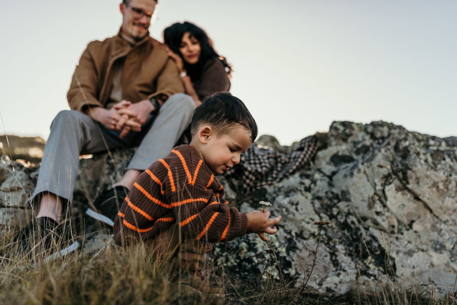 Family spending time together on a rocky outcrop during golden hour.