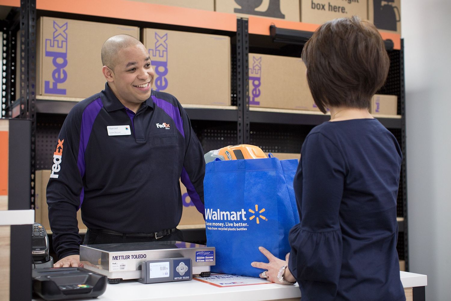 A FedEx Office associate discusses shipping options with a customer.