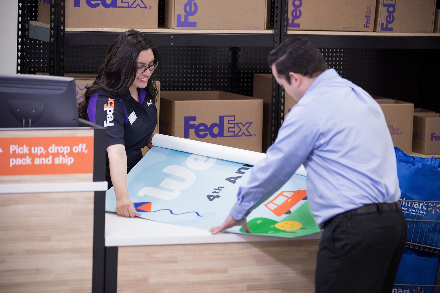 A FedEx Office associate shows a customer the custom vinyl banner they ordered.