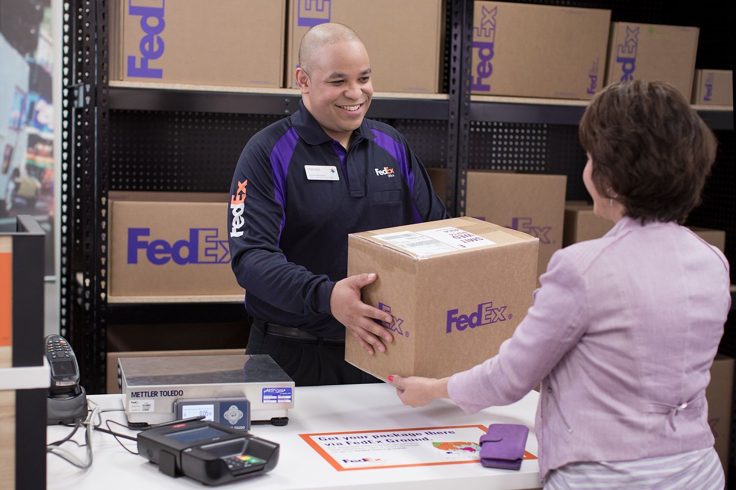 A woman picks up a package at a FedEx Office located in her local Walmart Supercenter.