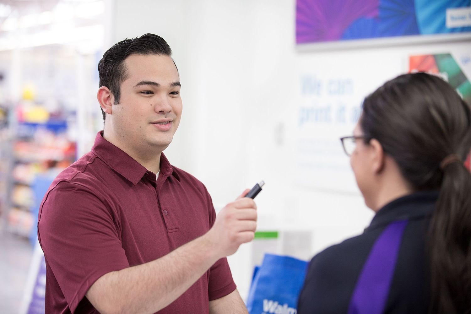 A customer hands a FedEx Office associate a USB drive filled with documents that will be printed and shipped.
