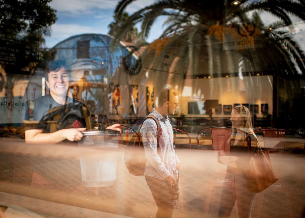 double expose of palm trees and friends chatting outside of brewery in santa barbara