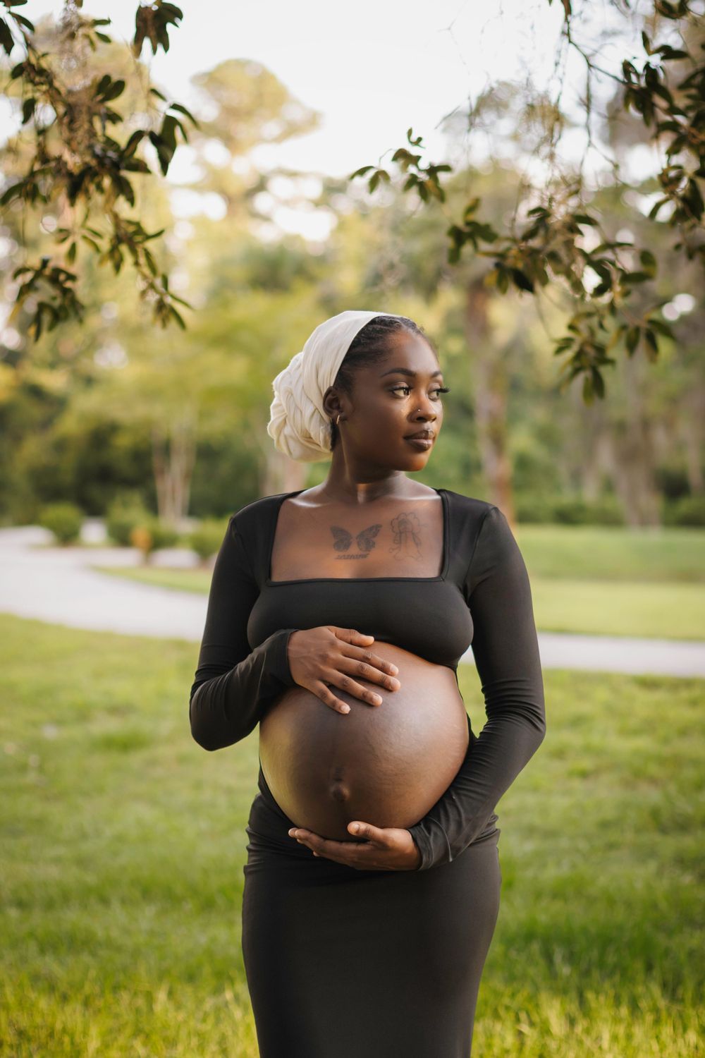 Outdoor maternity portrait in a black dress with natural garden scenery.