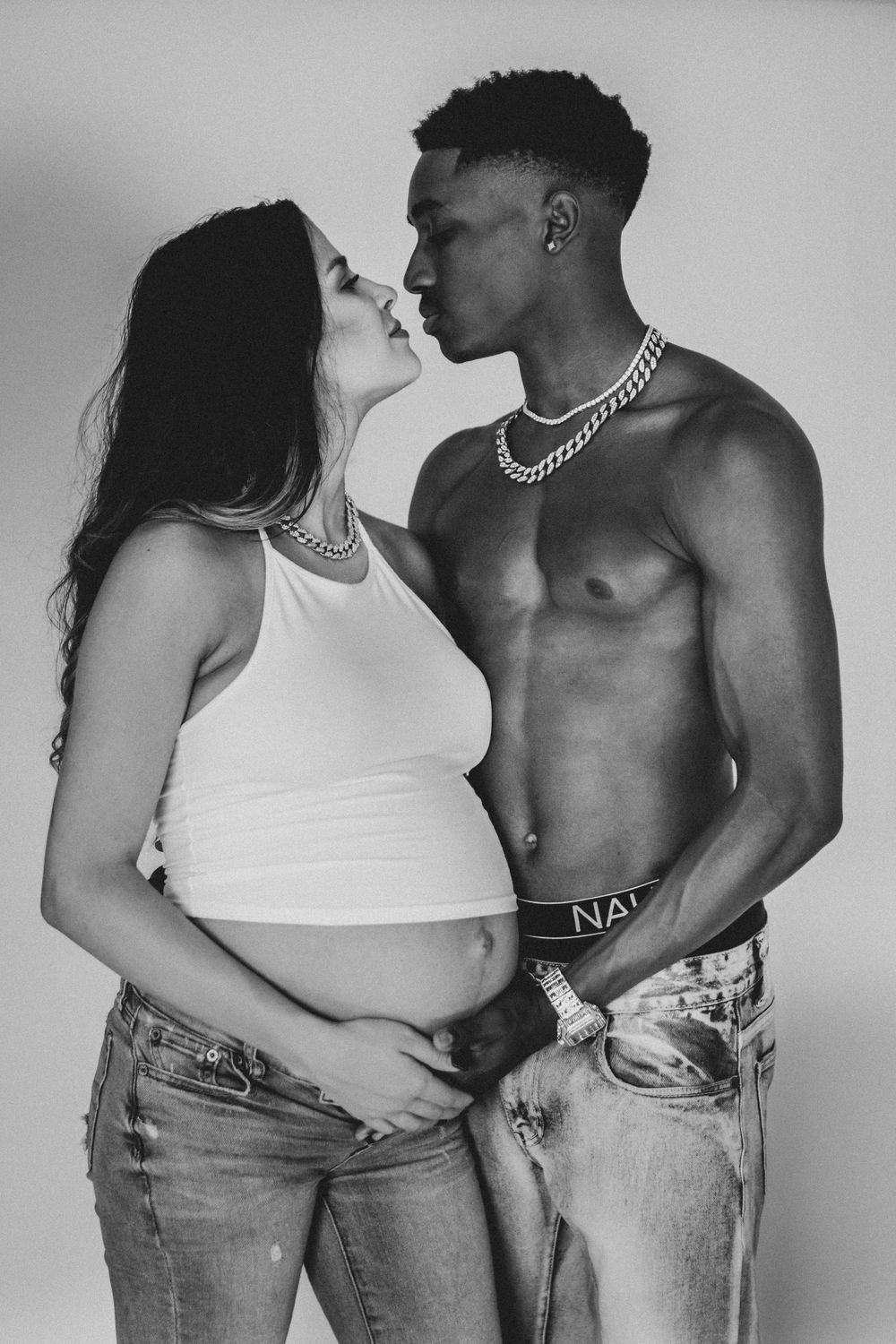 Black and white intimate maternity photo with couple in casual attire.