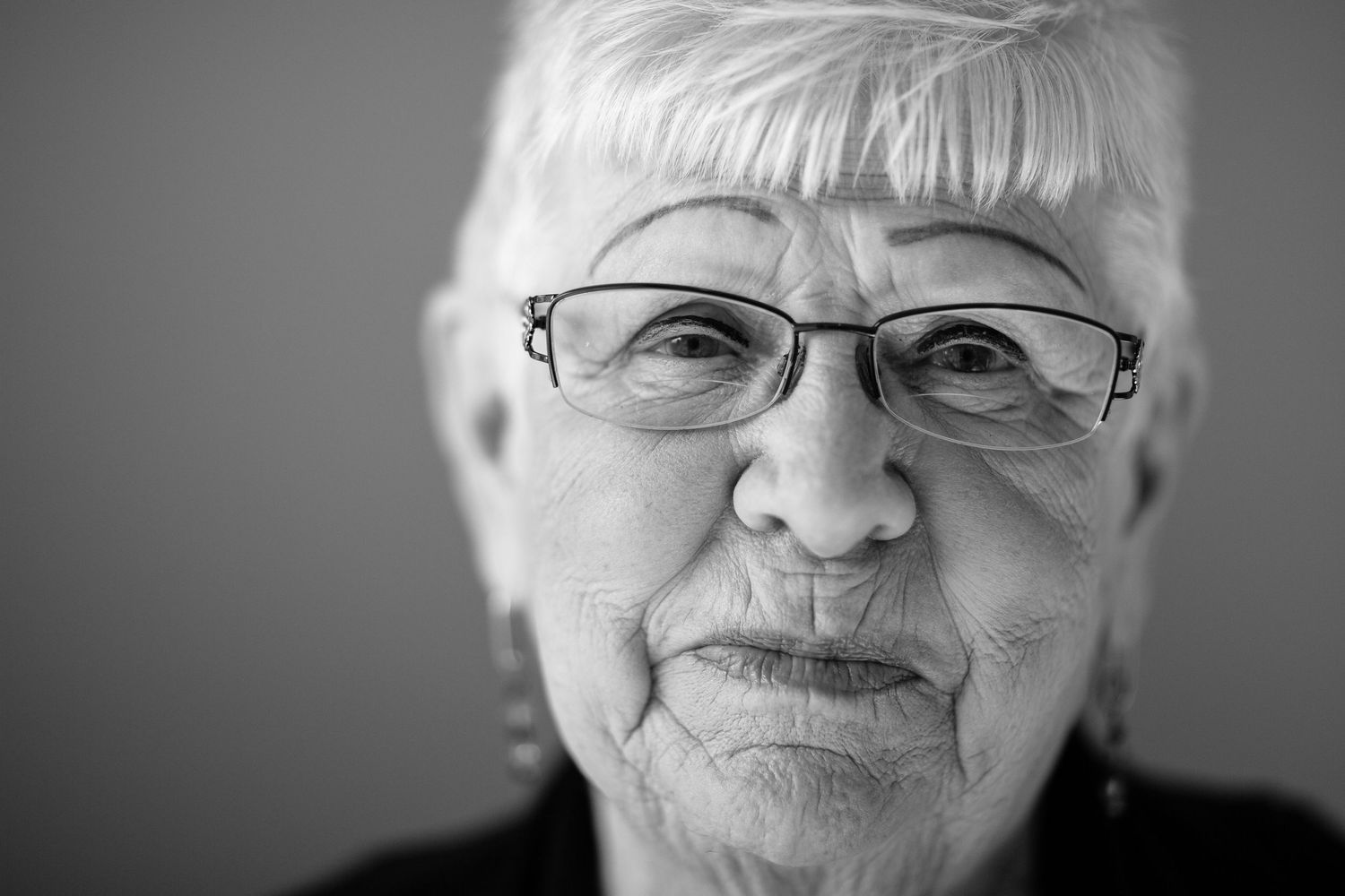 Close-up black and white portrait of senior woman wearing glasses.