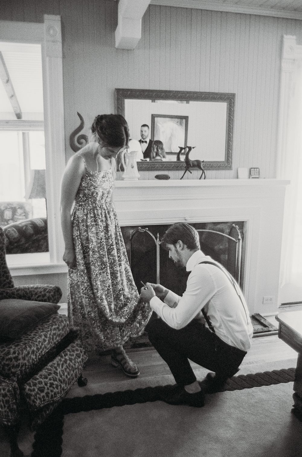 A couple shares an intimate moment in front of a fireplace during wedding preparations.
