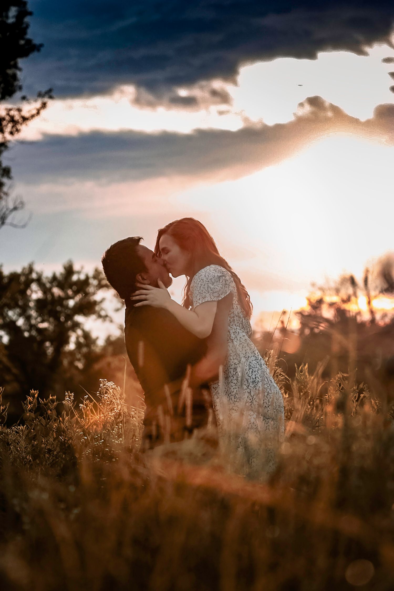 Romantic sunset silhouette of a couple embracing in a golden field.