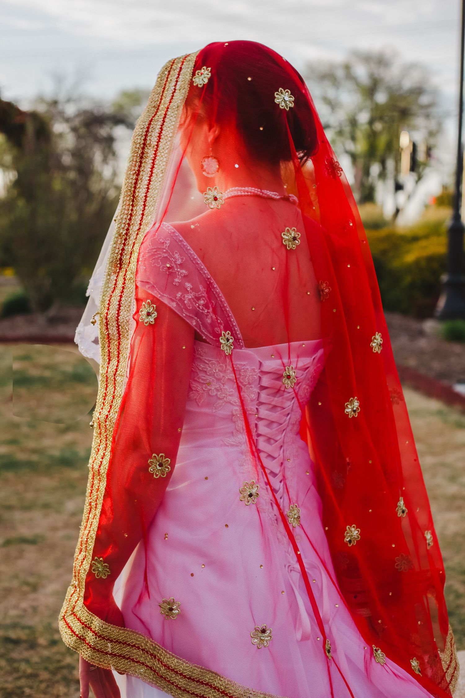A pink dress with a red embroidered veil creates a stunning fusion of traditional and modern bridal fashion.