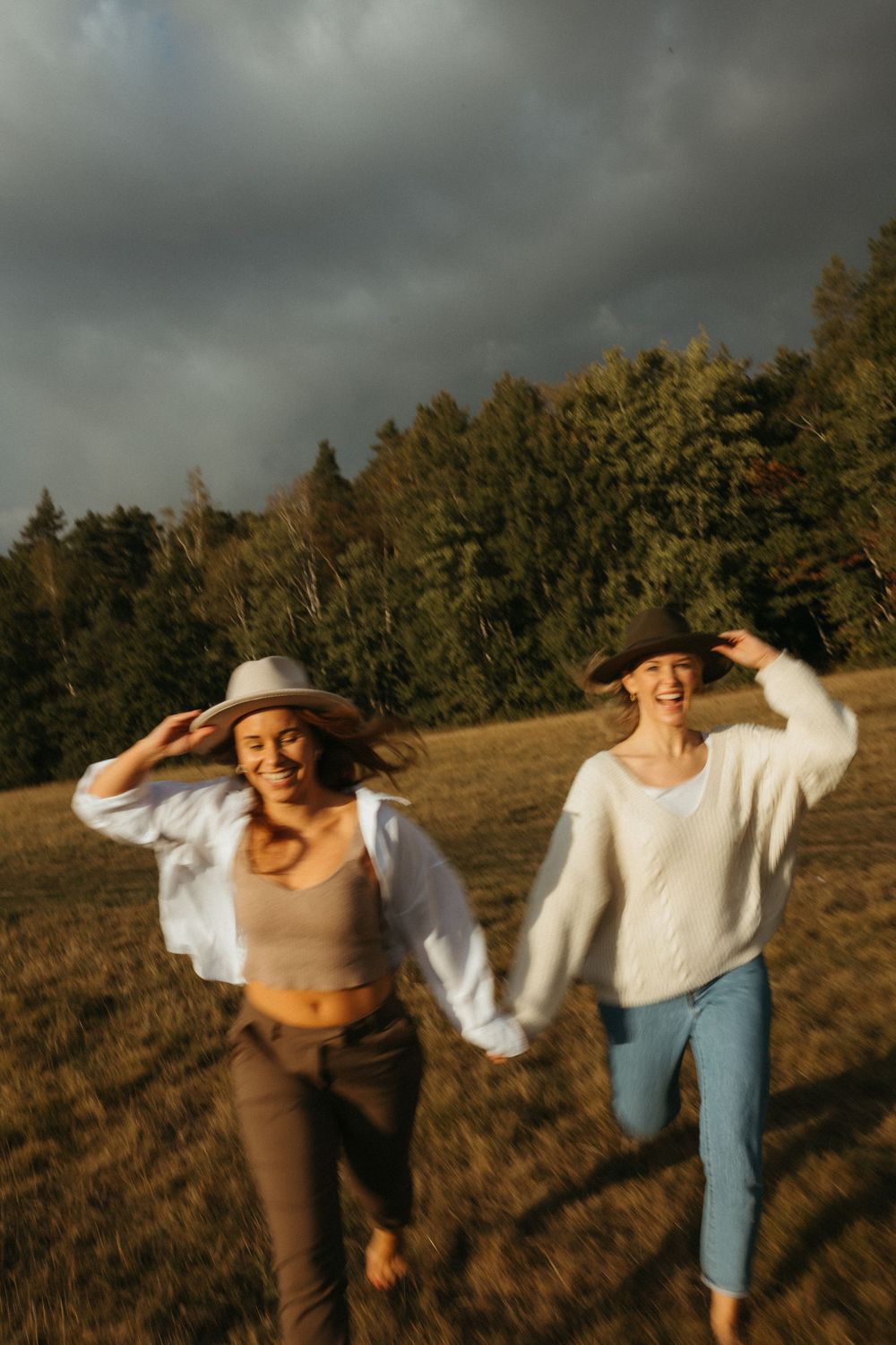 Candid moment of people laughing and dancing together on a hill during golden hour.