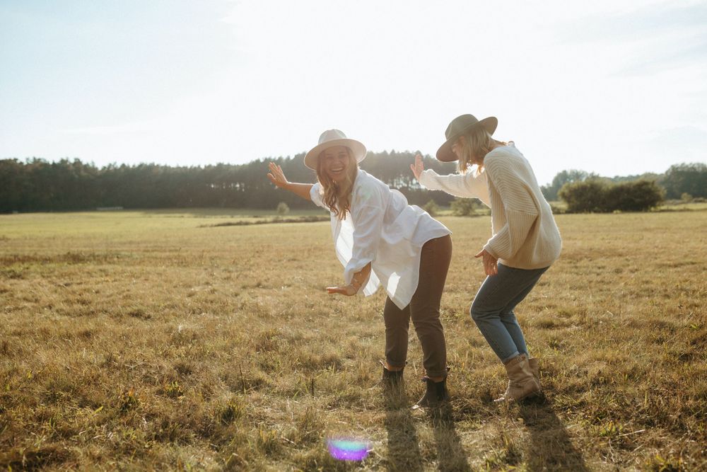 People run and dance playfully through a golden field at sunset.