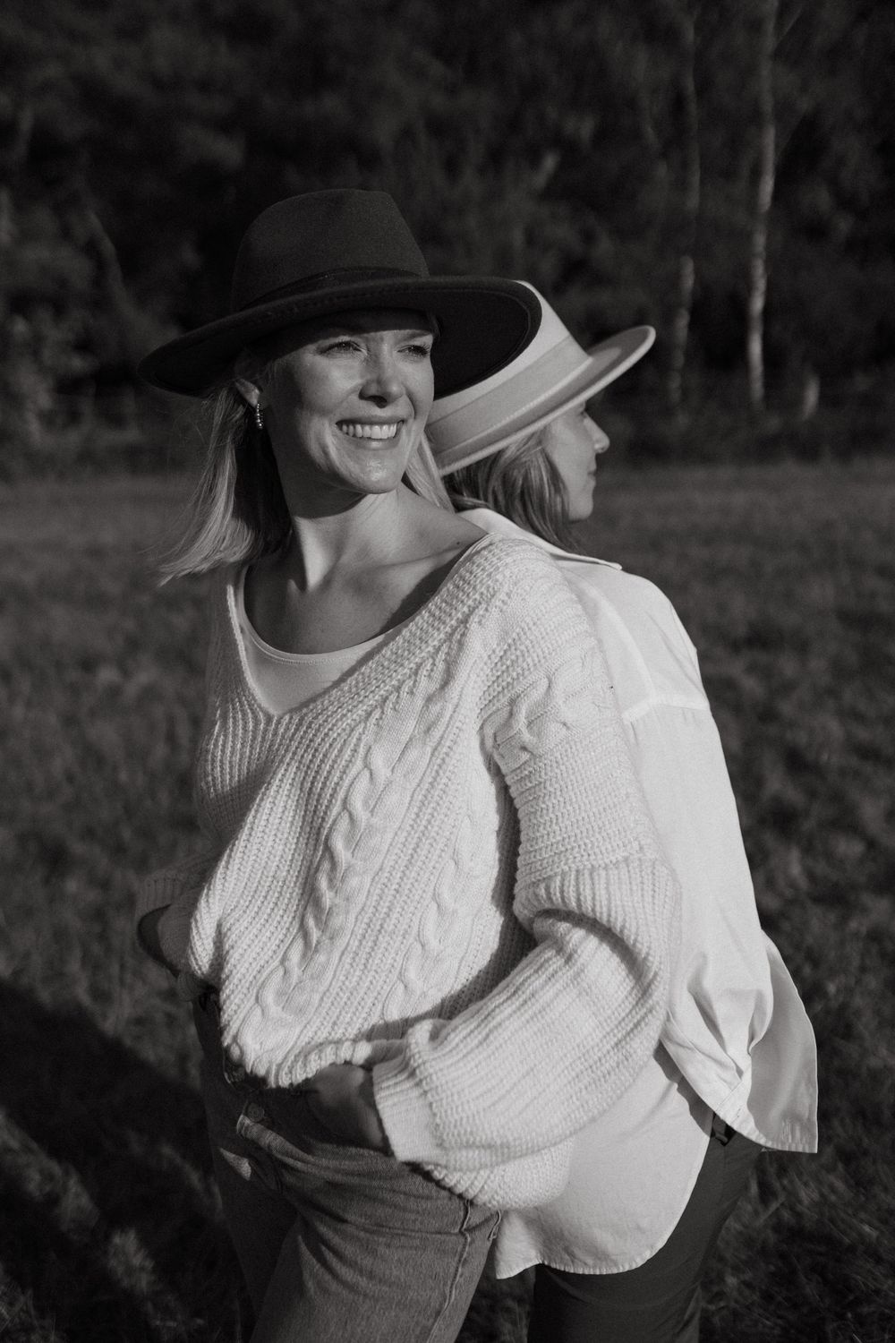 Black and white portrait of someone in a cozy knit sweater and wide-brimmed hat.