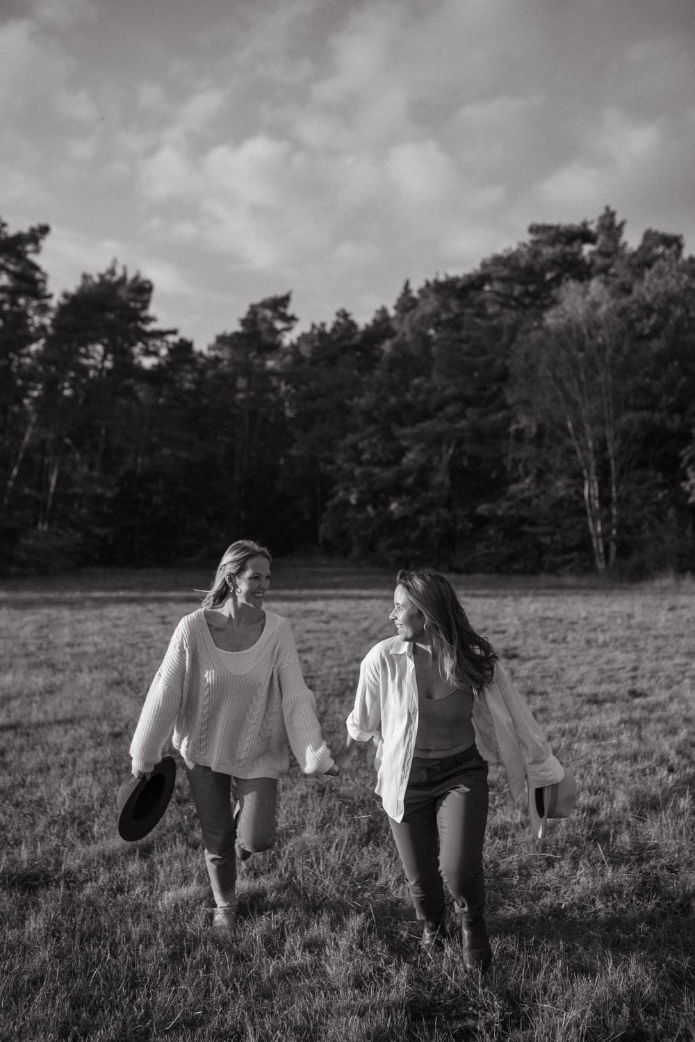 Black and white photo of friends walking through a rustic meadow at dusk.