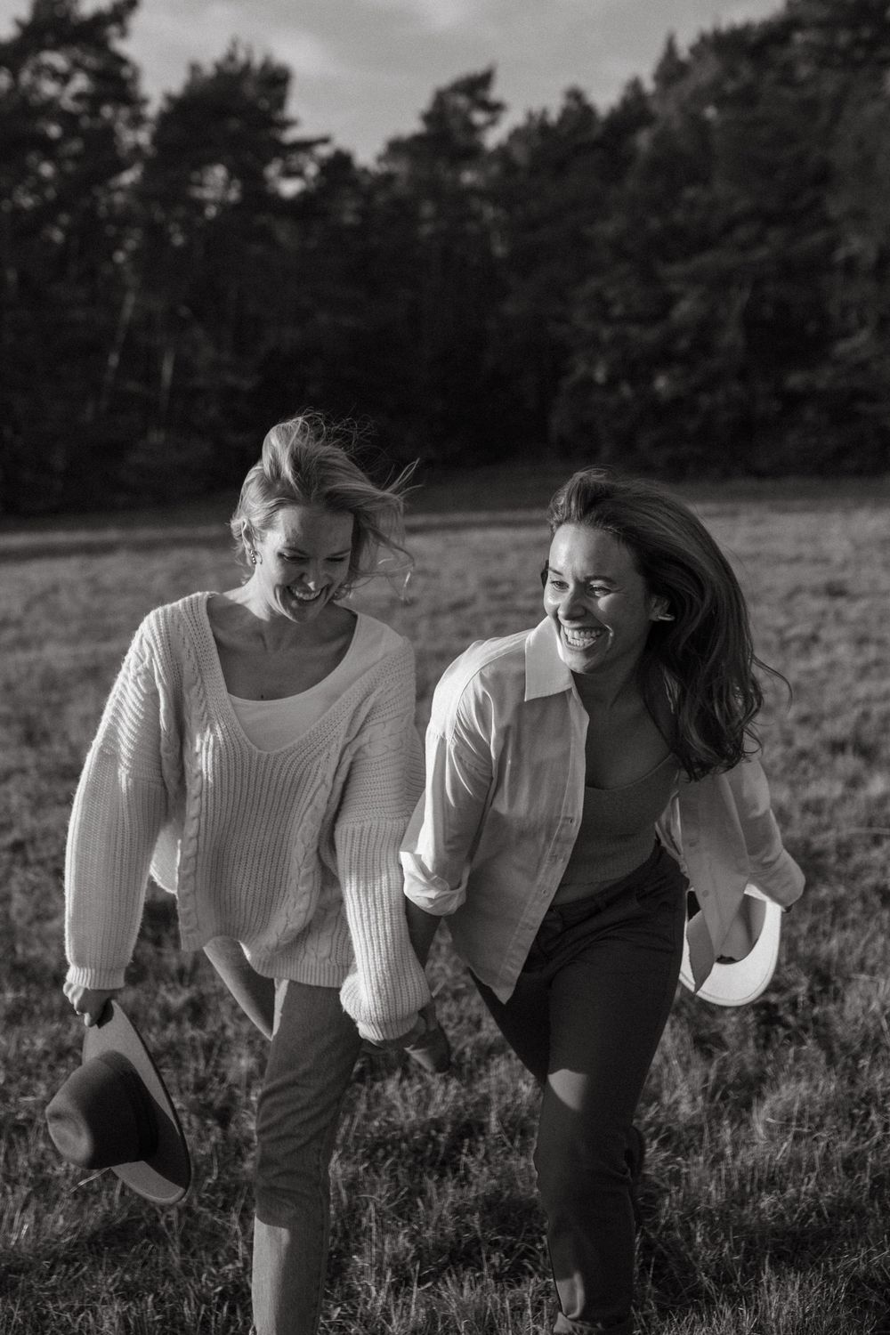 Friends share joyful moments in an autumn field near woods.