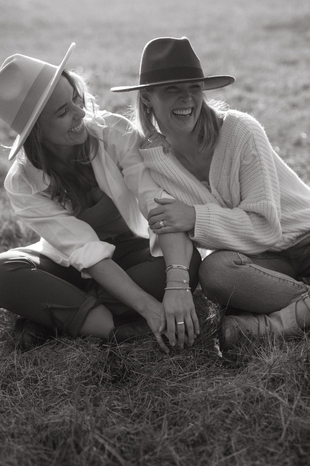 Black and white candid shot of friends relaxing together on grass wearing casual outfits.