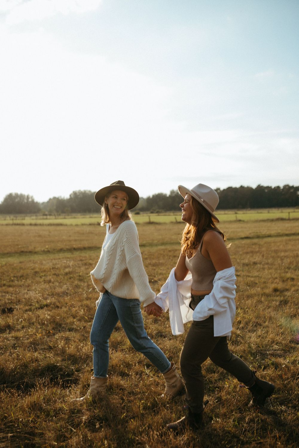 Playful moments captured in a sun-drenched field with friends in western-inspired outfits.