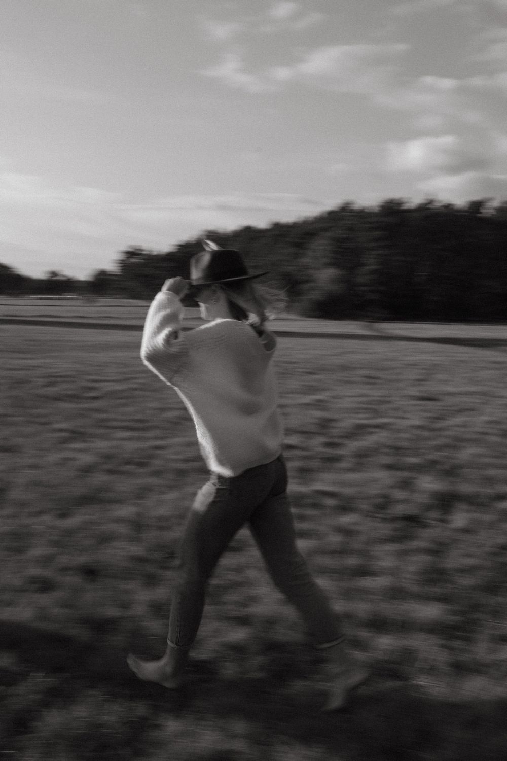 Black and white photo capturing energetic dance movements in an open field.