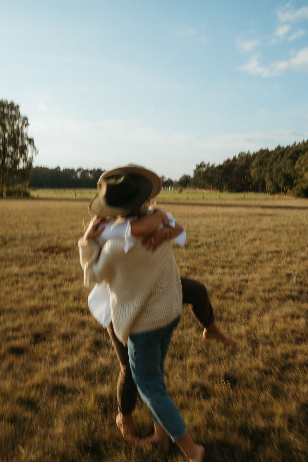 People run and spin joyfully through a sun-drenched meadow.