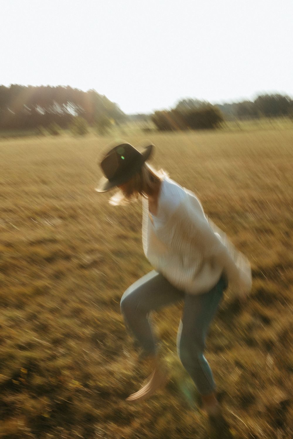 People playfully jumping and dancing in a sunlit autumn field at sunset.