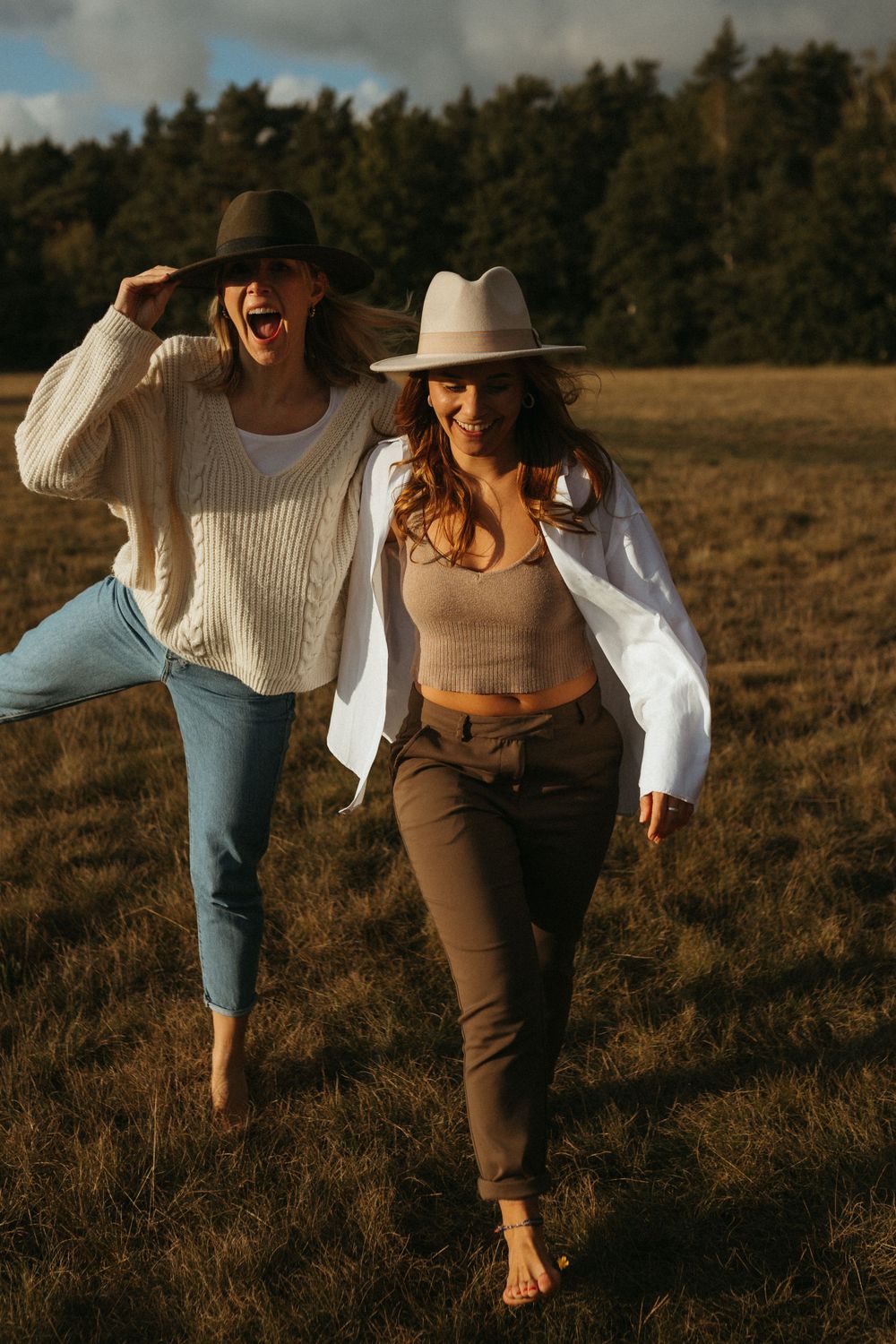 Friends dance together in warm sunlight across an autumn field.