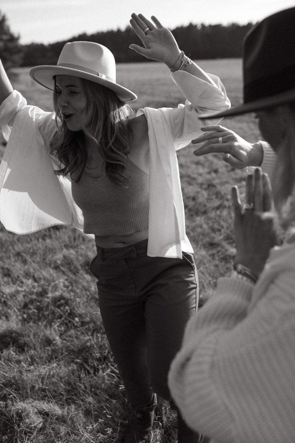 Black and white photo of friends dancing and laughing in an open field.