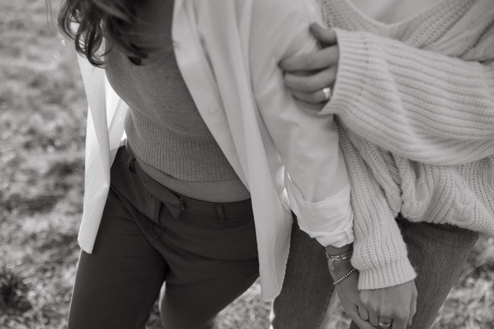 A candid black and white close-up shot of two people laughing and embracing in casual attire.