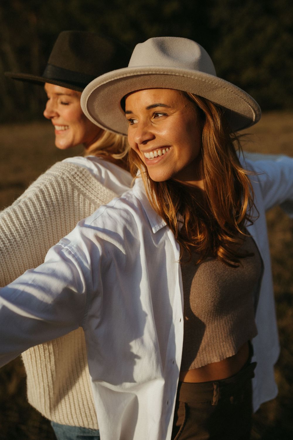 Friends embracing and laughing together in golden hour lighting.