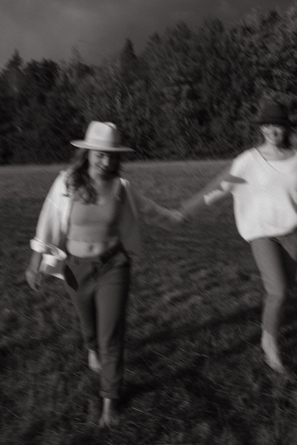 Blurred motion shot of people dancing freely in a grassy field at sunset.