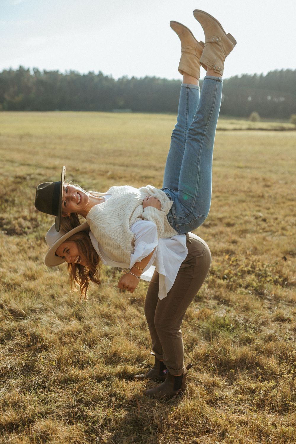 Playful piggyback rides in a sunlit field wearing casual western-inspired clothing.