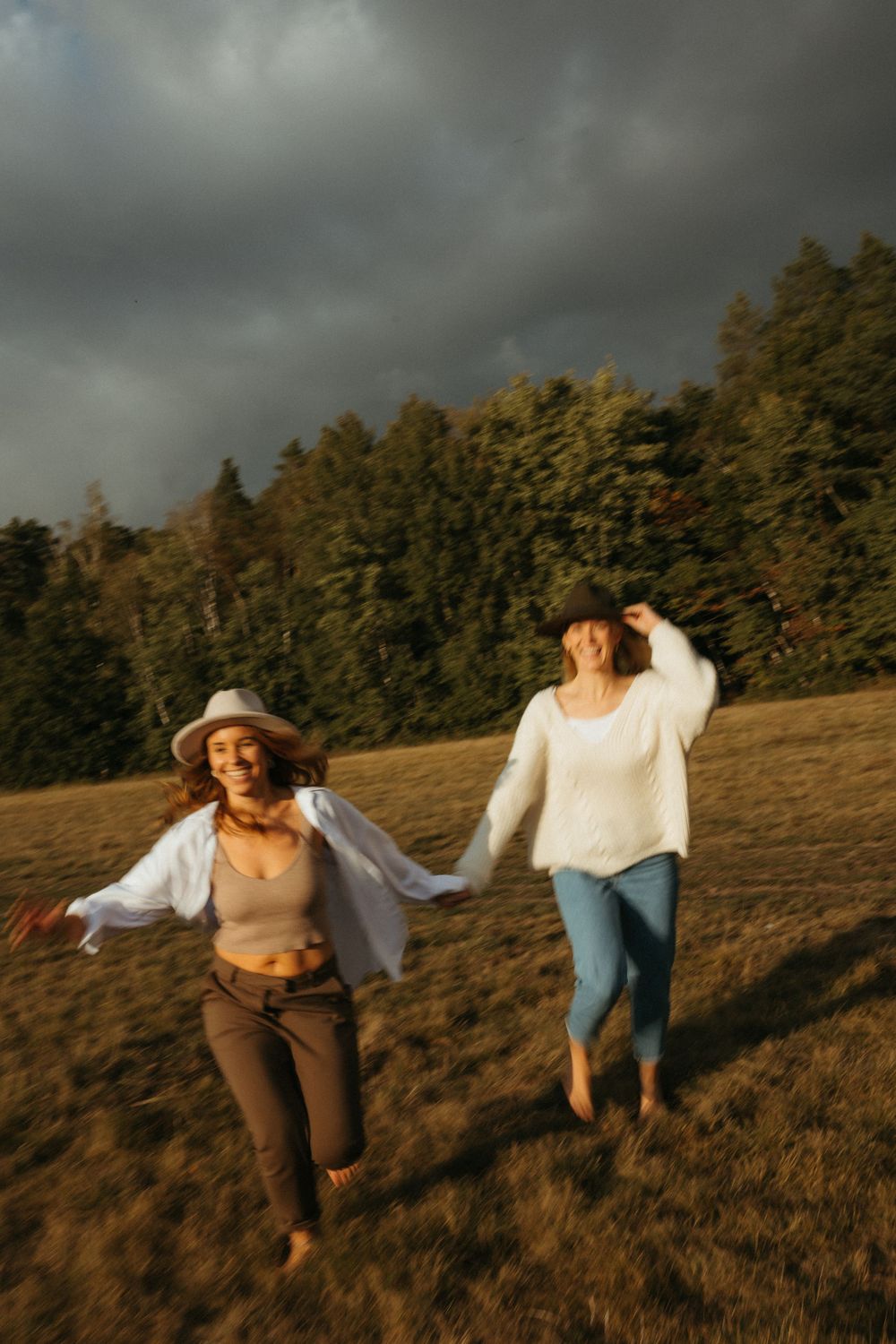 People dancing joyfully across a golden hillside during sunset with trees in background.