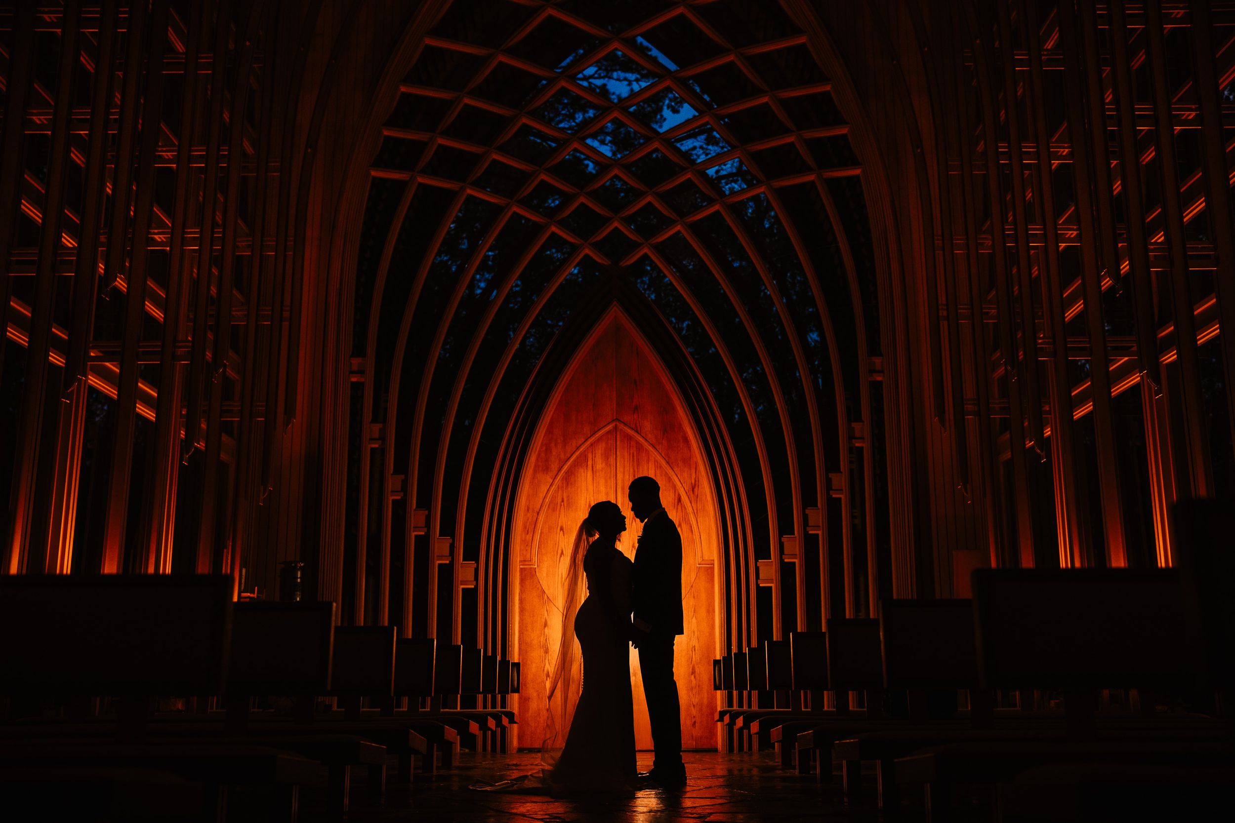 Silhouette of a couple standing in a dramatically lit cathedral with arched gothic architecture.