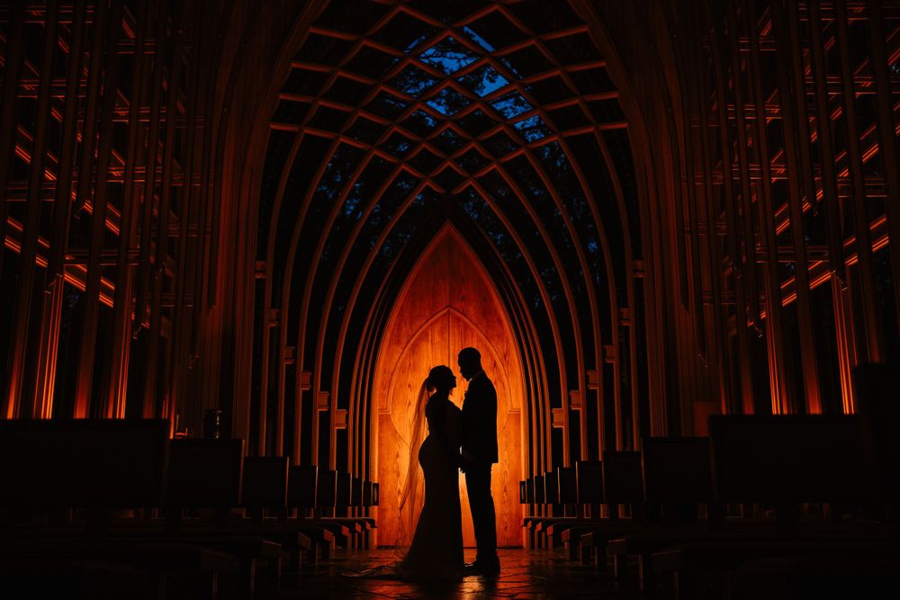 Silhouette of a couple standing in a dramatically lit cathedral with arched gothic architecture.