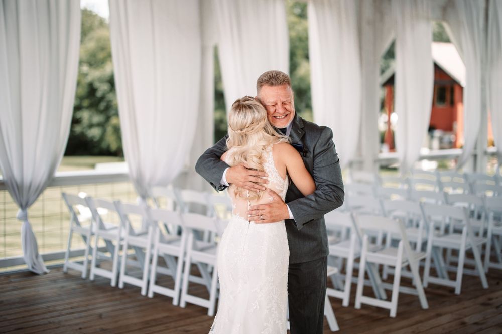 A touching moment between a couple sharing an embrace at their wedding venue with white chairs in background.