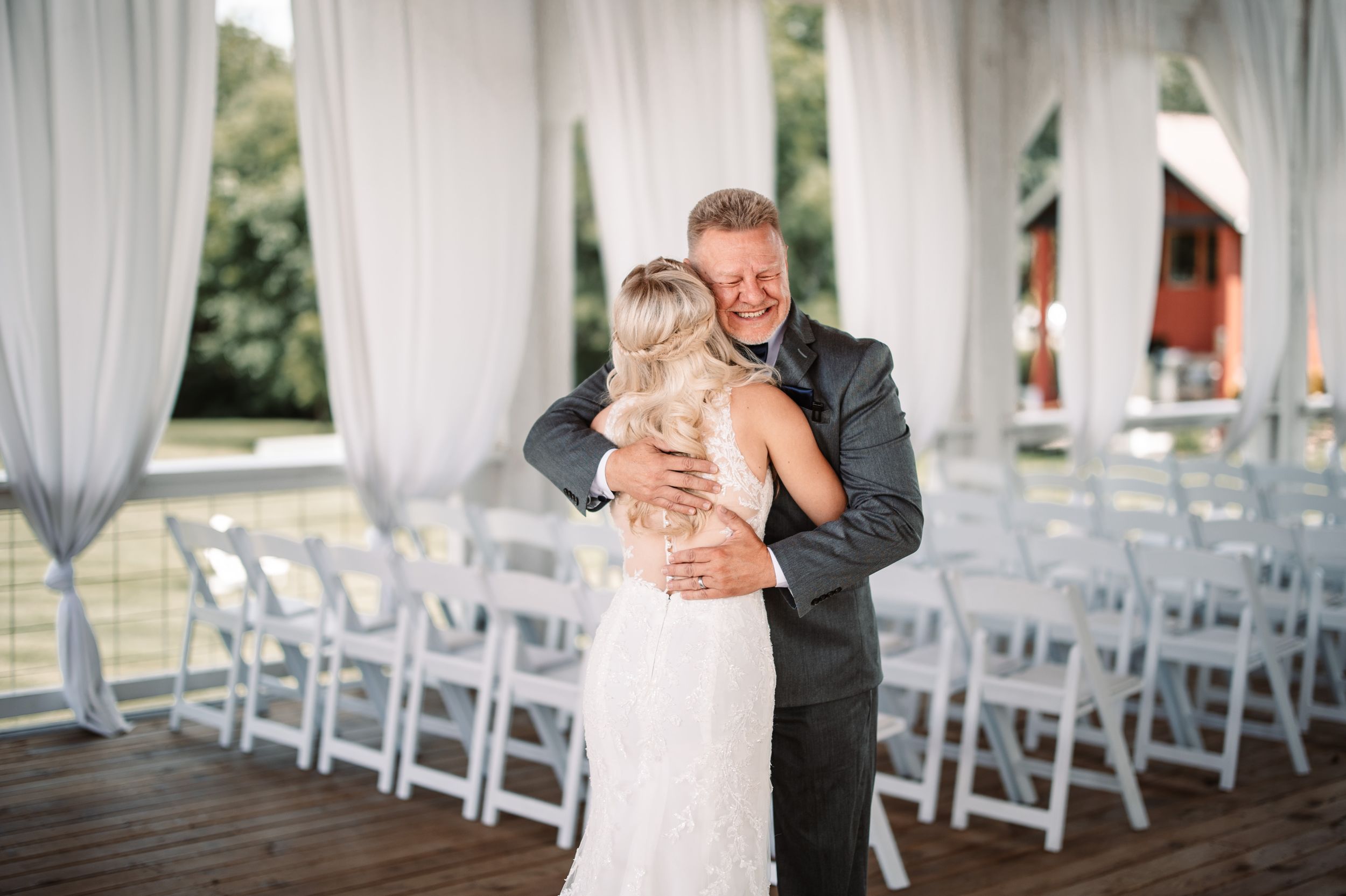 A touching moment between a couple sharing an embrace at their wedding venue with white chairs in background.