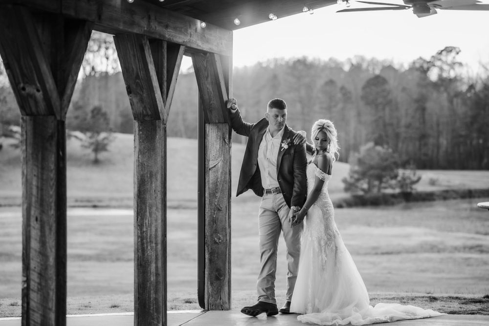A couple poses under a wooden pavilion with dramatic black and white lighting.