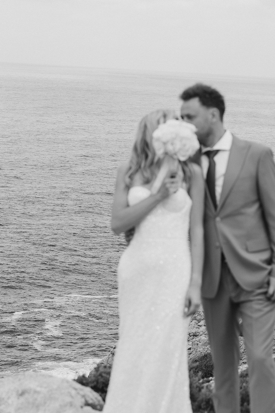a couple kissing behind a bouquet of flowers