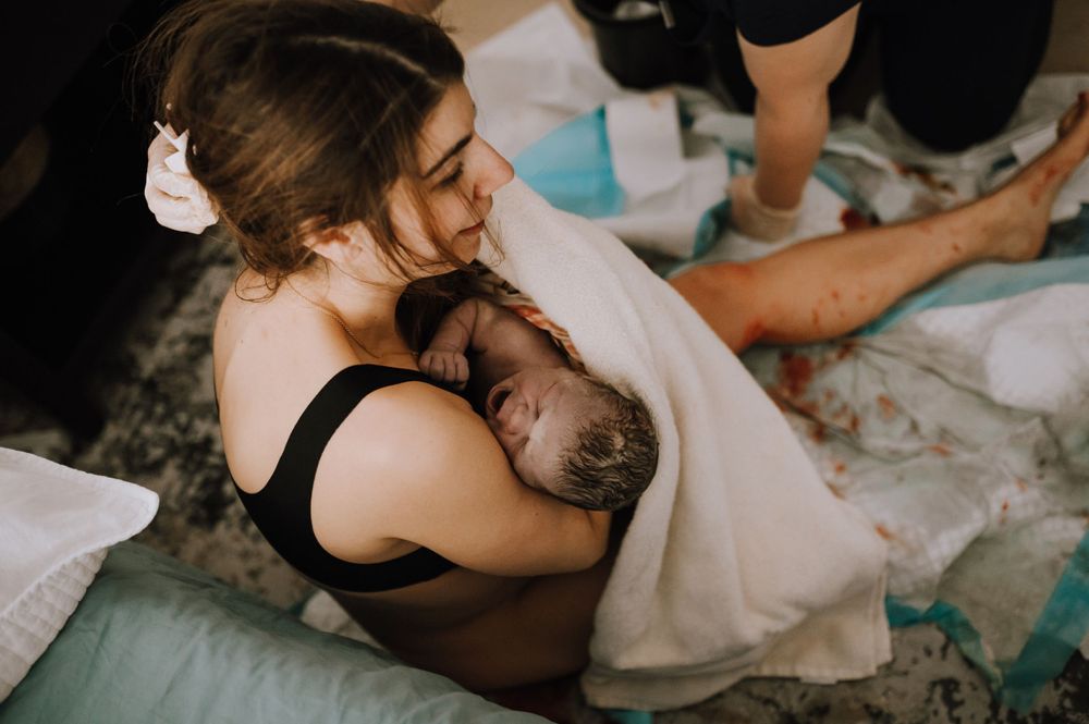 Intimate moment during natural childbirth as doula and medical team provide support.