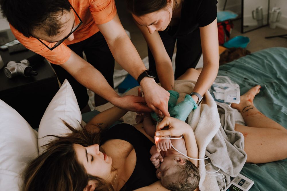 Multiple people gathered closely together on bedding in an intimate indoor setting.