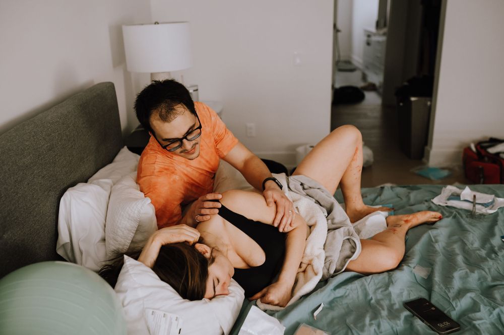 Two people rest together on a couch in a candid home setting with casual attire and relaxed poses.