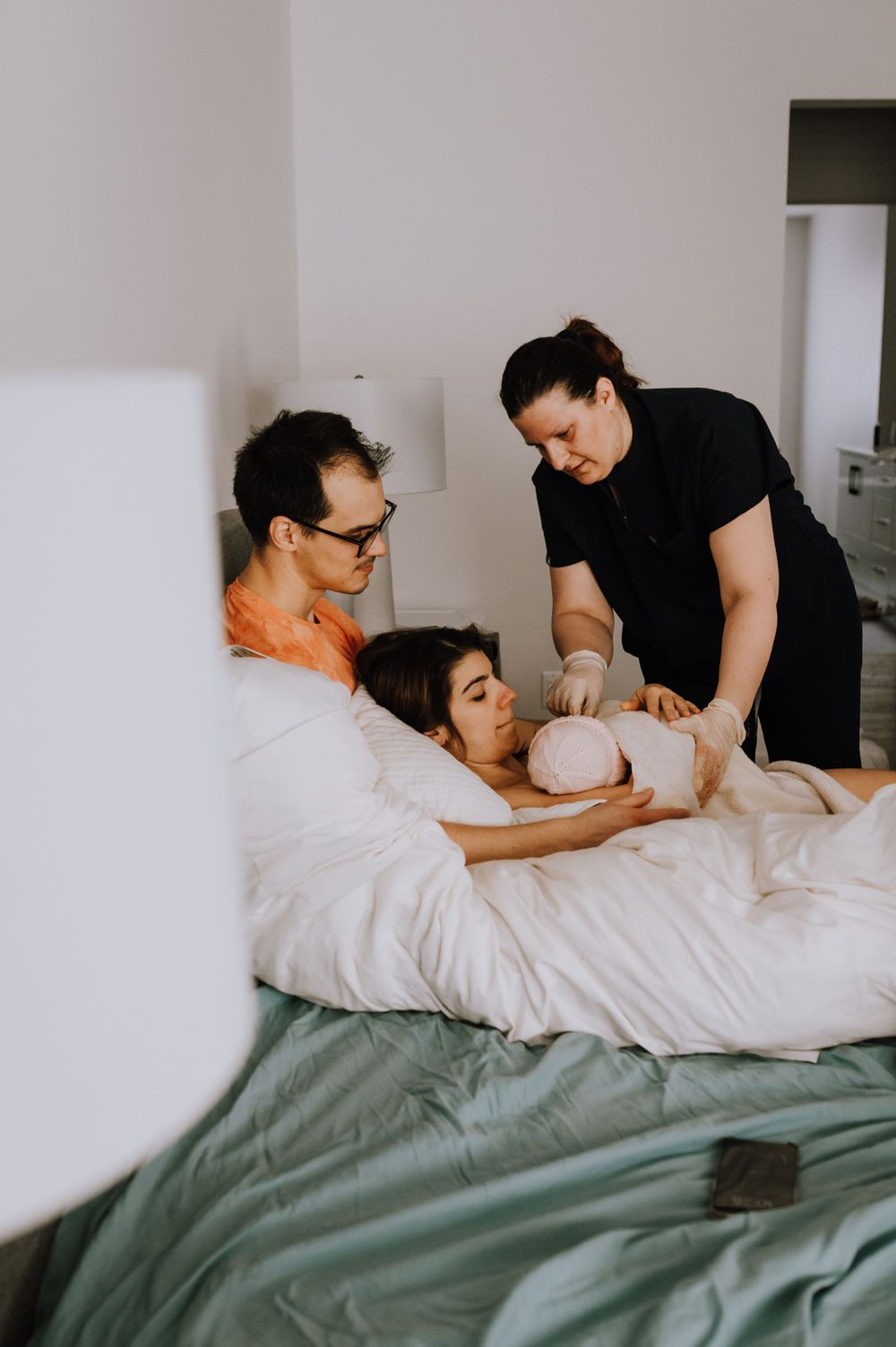 Healthcare team assists during home birth in peaceful bedroom setting.