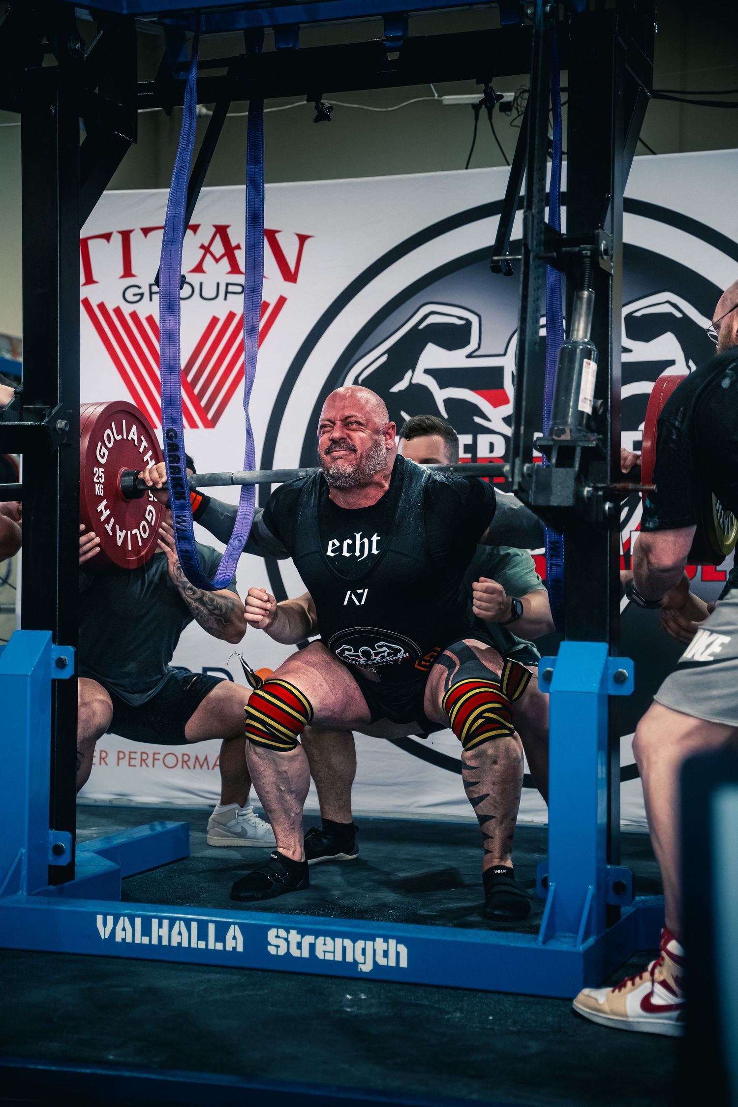 Powerlifter performs heavy squat on blue competition bench at Valhalla Strength event.