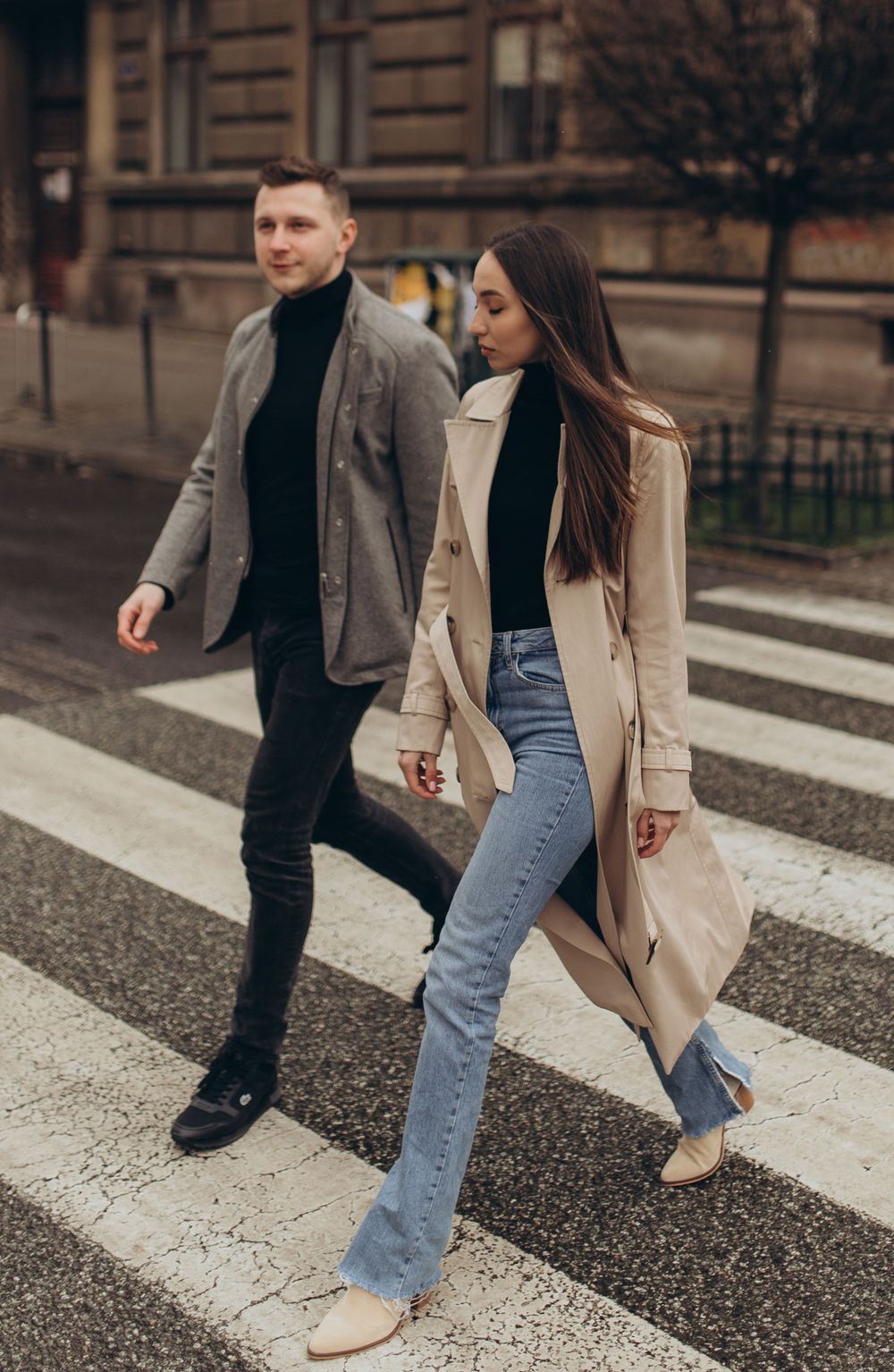 Fashion-forward couple crossing street in coordinated neutral tones and trendy casual wear.