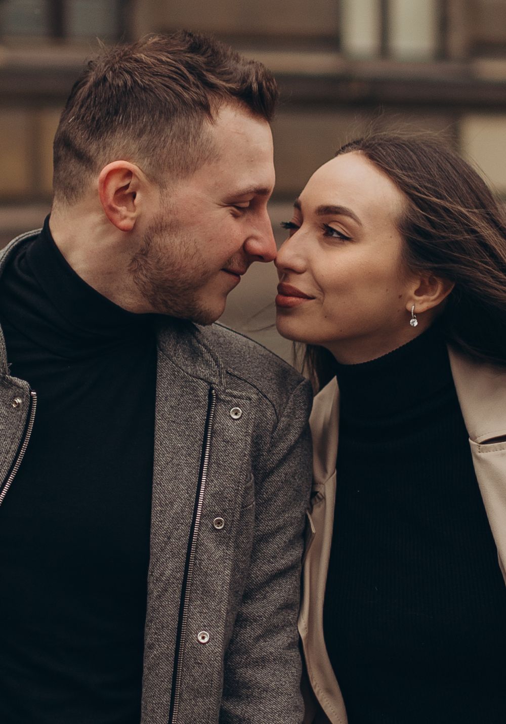 Intimate close-up portrait of couple sharing tender moment against brick building backdrop.