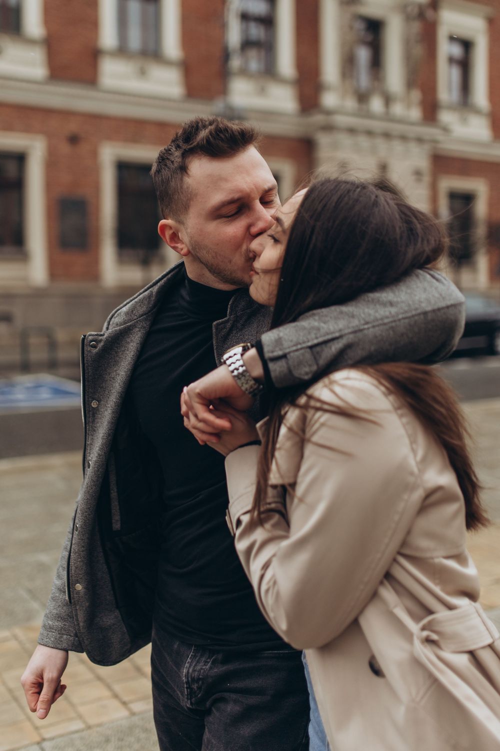Candid romantic moment captured between couple in coordinated winter outfits.