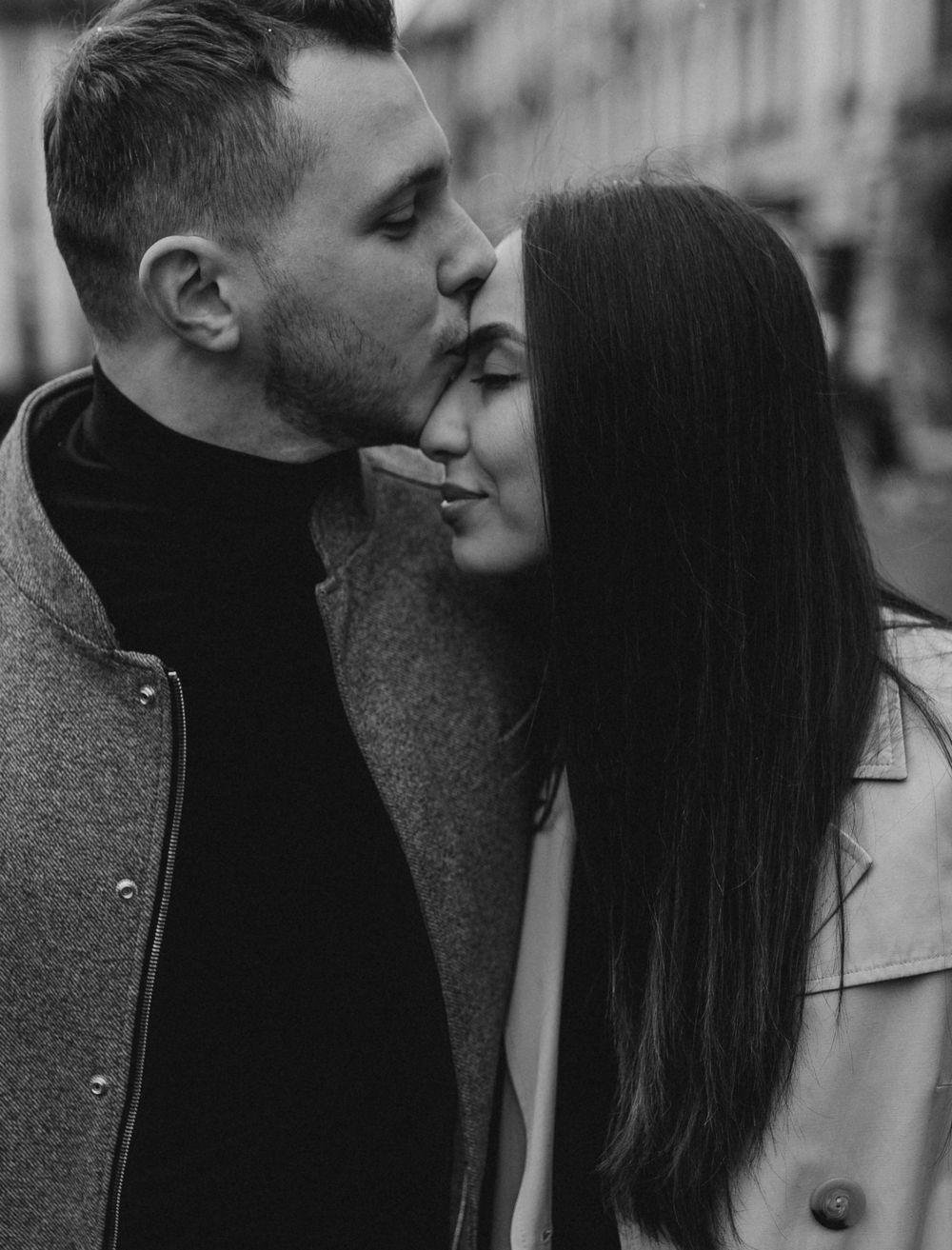 A romantic couple sharing an intimate moment in black and white on a city street.