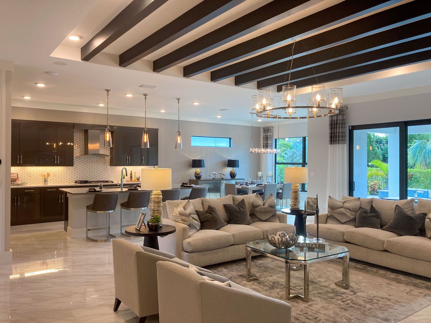 Modern open concept living room with exposed wooden beams and neutral toned furniture.