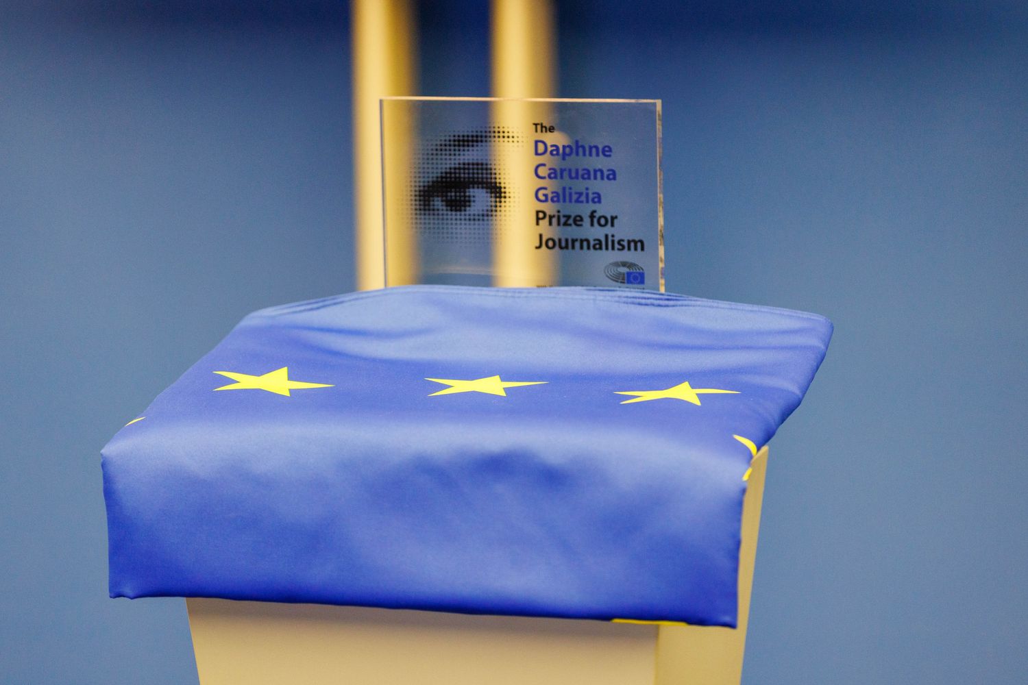An EU flag draped over a podium with illuminated columns in the background.