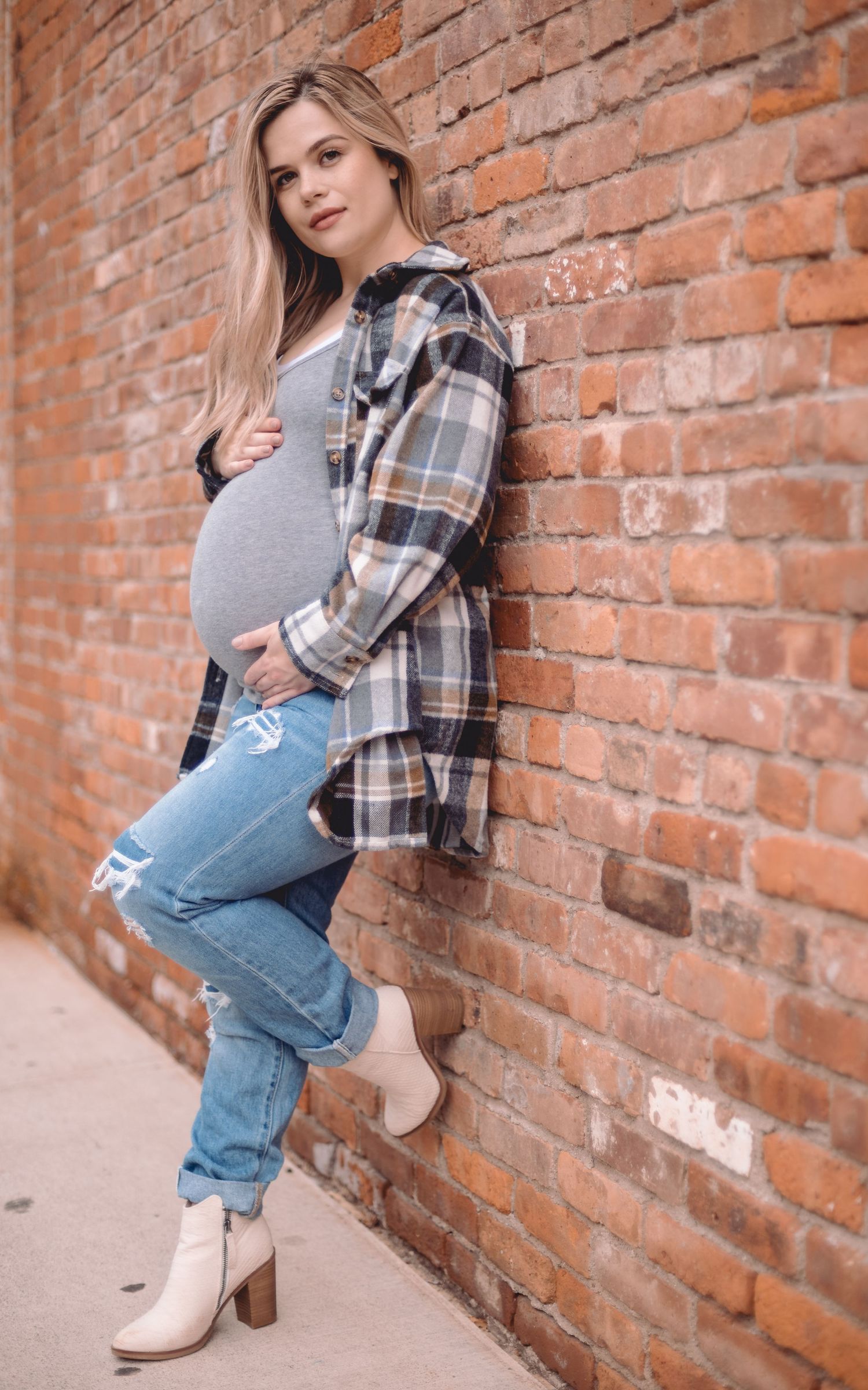 pregnant woman leaning up against a brick wall
